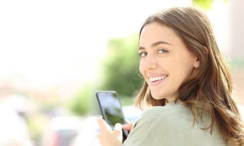 Woman with dental bridge in Worcester smiling on phone