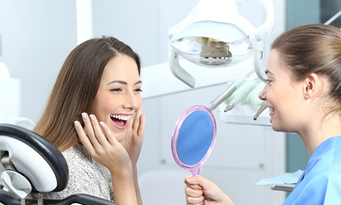 Woman admiring her smile after dental checkup and cleaning in Worcester