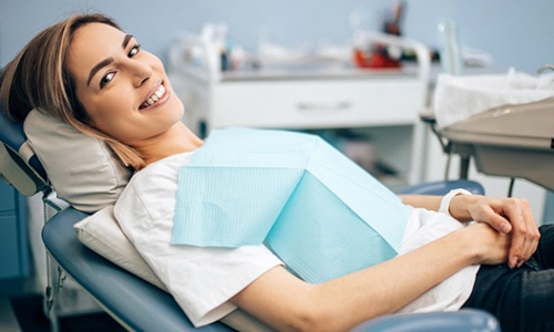 A young female lying back in the dentist’s chair and smiling after receiving a tooth-colored filling by her family dentist in Worcester
