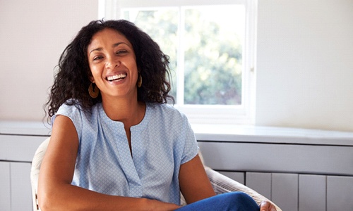 Woman in blue shirt smiling while relaxing in chair