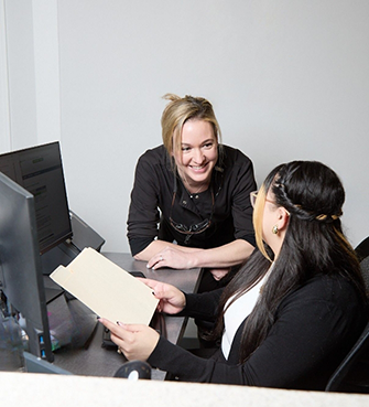 Two dental team members talking at a desk