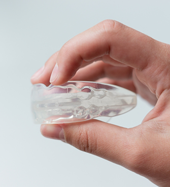 Hand holding a clear mouthguard