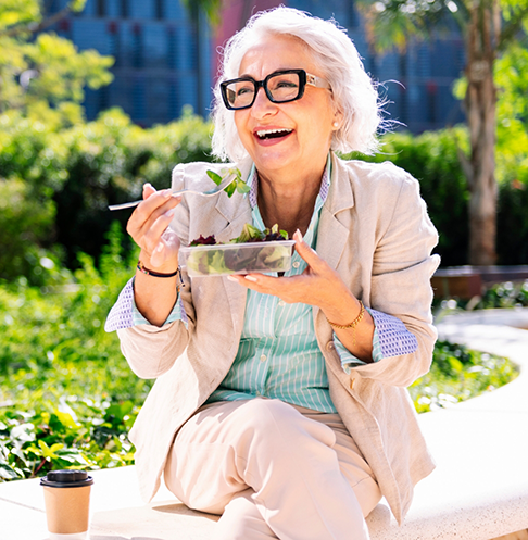 Woman eating salad on outdoor bench