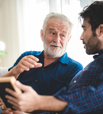 Older man sitting next to younger man on couch