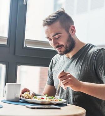Young man eating salad at table