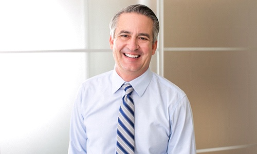 man in light blue dress shirt and tie smiling with dentures in Worcester