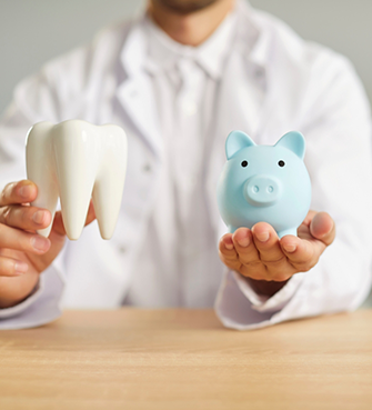 Dentist holding a piggy bank and a model of a tooth