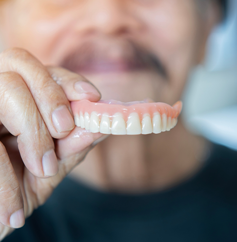 Man holding his denture