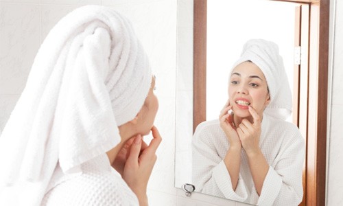 Woman looking at teeth and gums in bathroom mirror