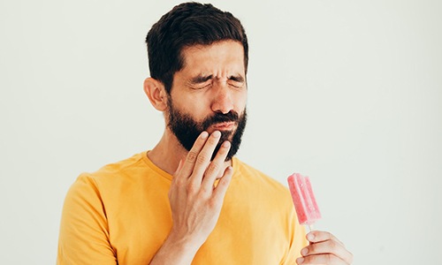 person eating a popsicle experiences dental sensitivity