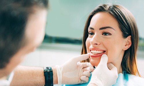 A dentist performing an oral cancer screening on a patient in Worcester