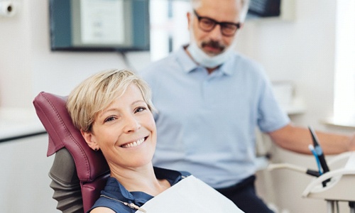 A middle-aged woman smiling after receiving an oral cancer screening in Worcester