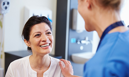 Woman in white shirt smiling at dental assistant