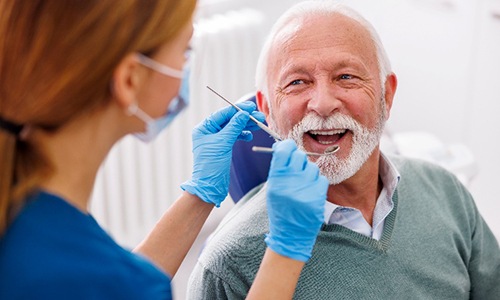 Senior man smiling during dental checkup with Worcester dentist