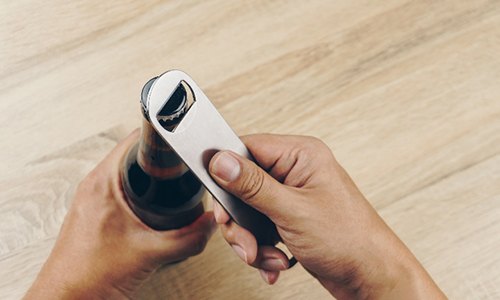 Closeup of male using bottle cap opener