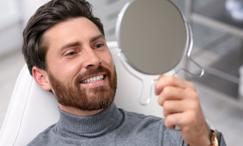 Man smiling in the mirror while in treatment chair 