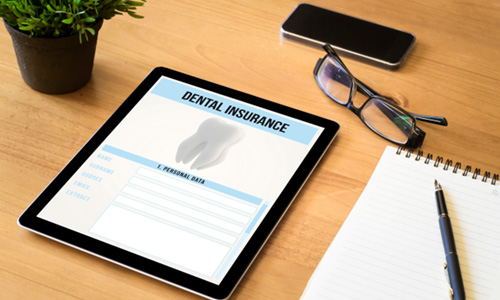Tablet with Dental Insurance on it and glasses 