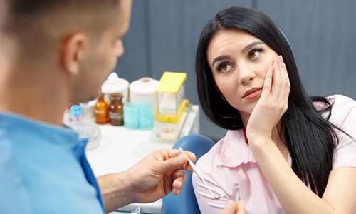 woman in pink shirt with tooth pain in dental chair