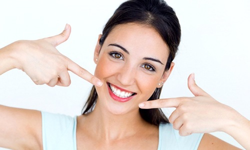 young woman pointing to her smile with white teeth