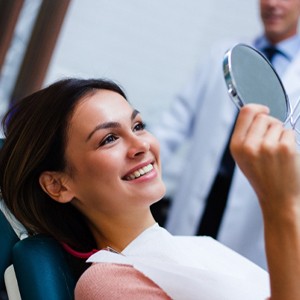 Woman with veneers in Worcester smiling in mirror