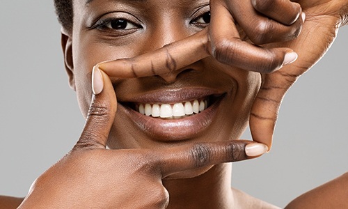 Woman framing her beautiful white teeth with her fingers