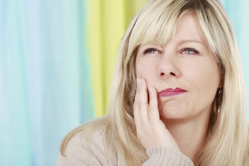 woman holding in jaw in pain