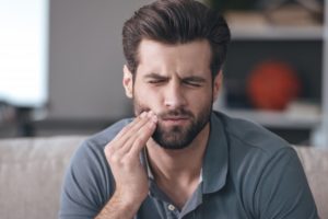 Pained man with cavity touching his cheek 