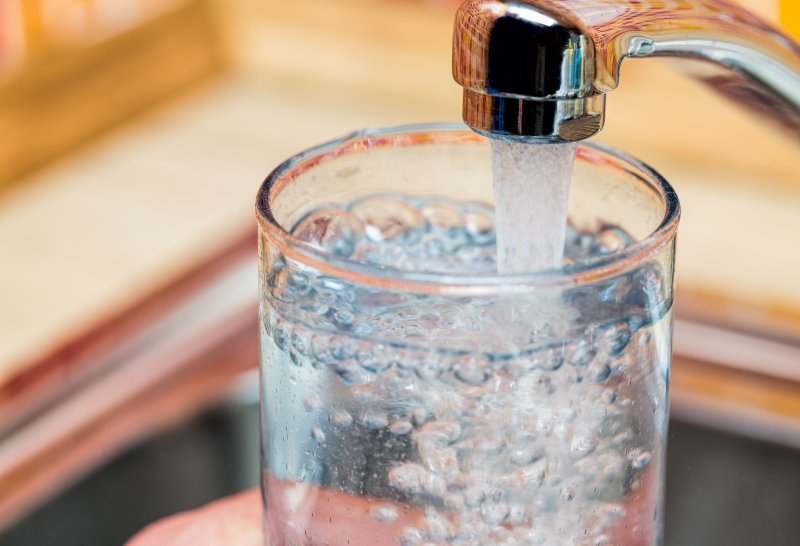 Person filling glass with tap water from sink