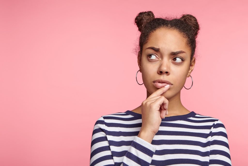 Closeup of woman wondering against pink background