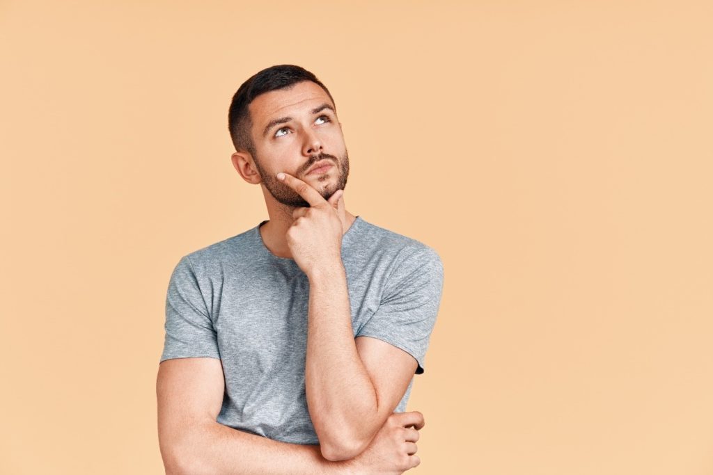 Man in gray shirt wondering about wisdom teeth