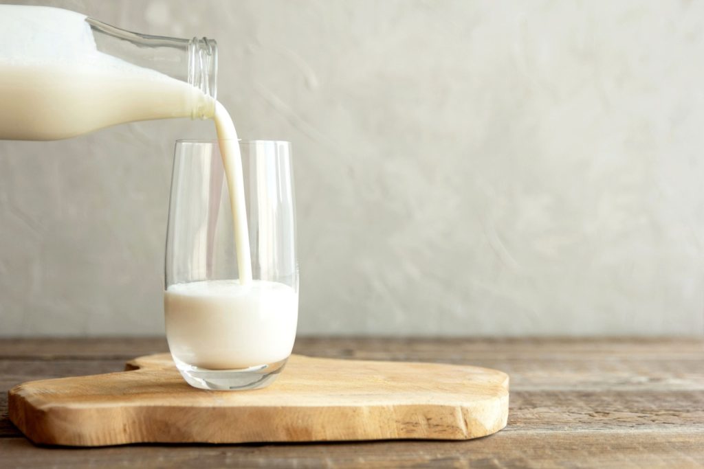 Person pouring milk into glass