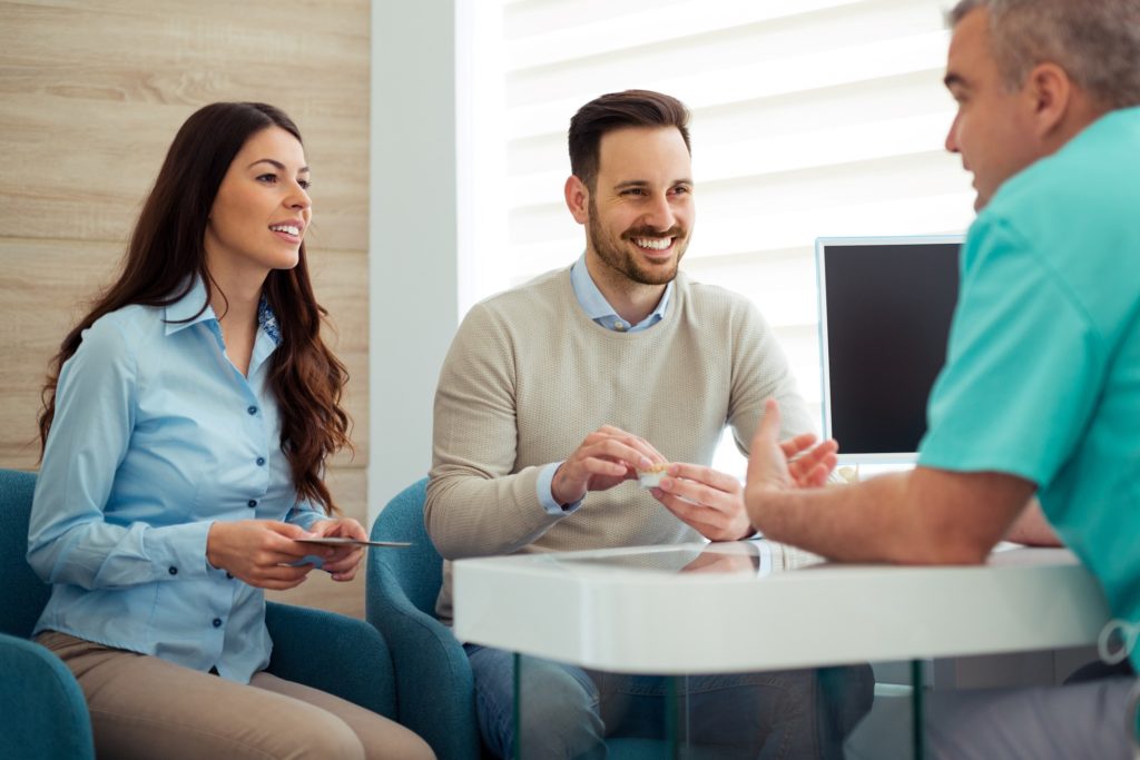 Dentist and couple talking in dental office