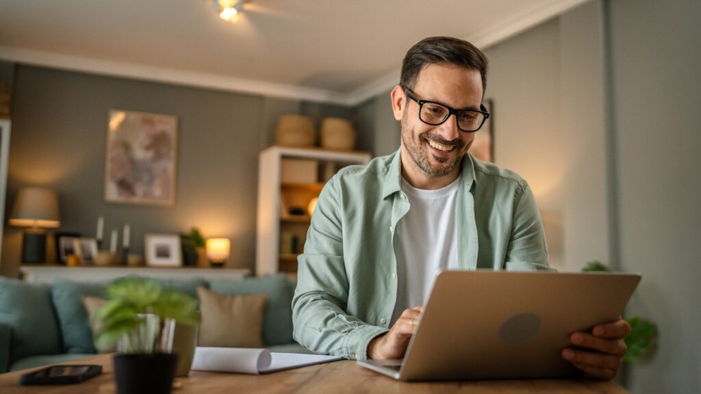 Man smiling while working on laptop at home